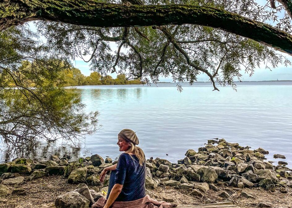 Vrouw onder boom met uitzicht op een meer