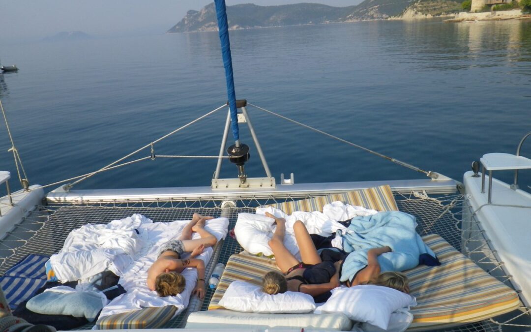 punt van een catamaran met slapen kinderen in het net tussen de twee boegen